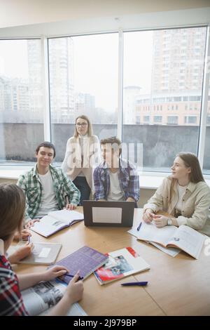 Vertical shot of a group of university students having discussion during class with their professor Stock Photo