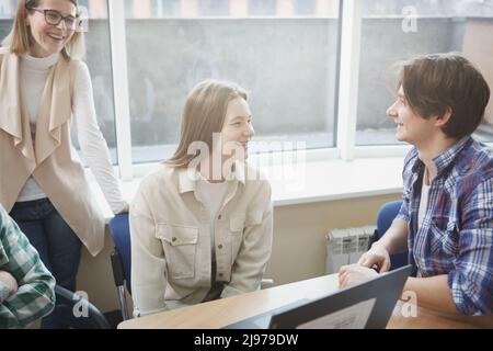 Cheerful college students and their teacher laughing, having discussion during class Stock Photo