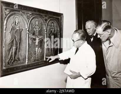 Group of german scientists examinating paintings to be returned from Kaiser Wilhelm Institute in Berlin to the federal government of Germany. The picture shows the oldest piece in the collection, a Westphalian altarpiece in three sections (c. 1250 - 1270). In the centre 'Holy Trinity', on the left 'Mary' and on the right 'John the Evangelist'. The restorer shows the already badly damaged parts of the painting Stock Photo