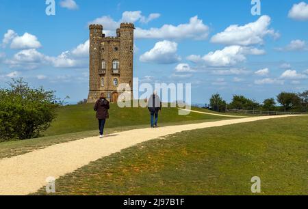 Sightseeing tourists walking towards Broadway Tower, an iconic and landmark of the Cotswolds, on Fish Hill, Broadway, Worcestershire, England, UK. Stock Photo