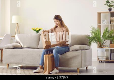 Happy woman who ordered things in online store takes box out of paper delivery bag Stock Photo