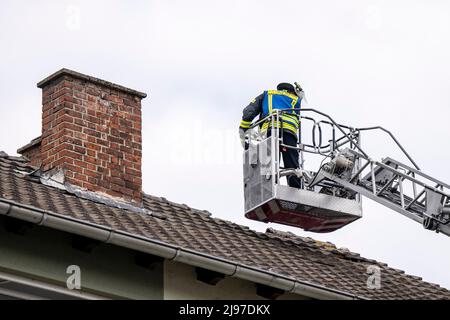 Lippstadt, Germany. 21st May, 2022. A firefighter checks the roof of a house. One day after the tornado, cleanup work has begun in the city center. Credit: David Inderlied/dpa/Alamy Live News Stock Photo