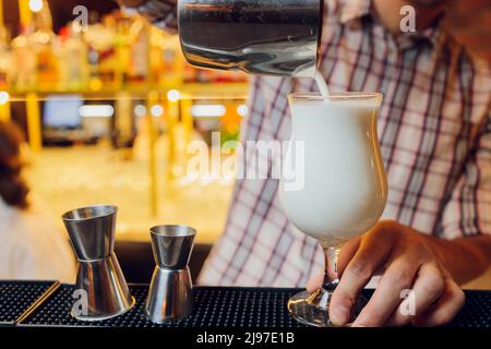 Close up shot of bartender hand pouring Cream mocktail in a glass from shaker Stock Photo