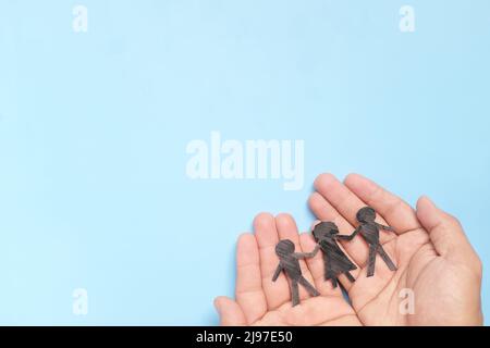 Hand holding children paper cutout. Child abuse rehabilitation, custody, human rights and refugee care and protection concept. Stock Photo