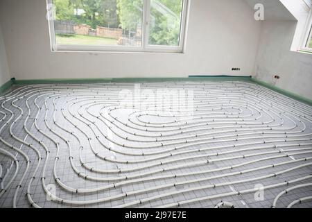Shot of construction site in a loft where underfloor heating has just been installed, white pipes on grey mat Stock Photo