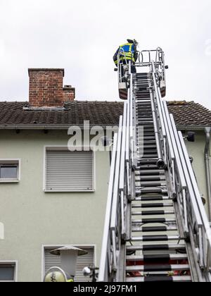 Lippstadt, Germany. 21st May, 2022. A firefighter checks the roof of a house. One day after the tornado, cleanup work has begun in the city center. Credit: David Inderlied/dpa/Alamy Live News Stock Photo