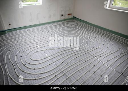 Shot of construction site in a loft where underfloor heating has just been installed, white pipes on grey mat Stock Photo