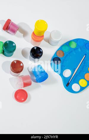 Jars with gouache multicolored paint, palette, brush. Top view.Flat lay. Stock Photo