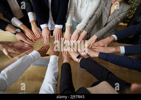 Team of successful and friendly business people fold their arms together in circle in support. Stock Photo