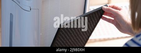 Woman removes filter from air purification system Stock Photo