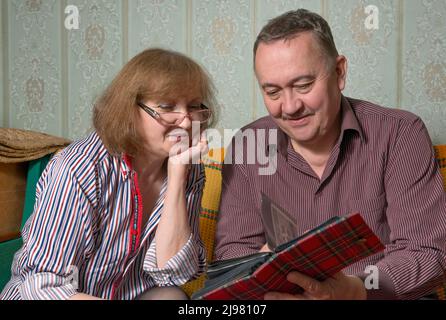 Closeup portrait of man and woman that are viewing photos in small album. Stock Photo