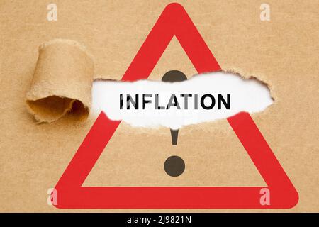 Word Inflation appearing behind torn brown paper on Attention road sign. Concept about increasing inflation rate and approaching financial crisis. Stock Photo