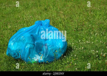 https://l450v.alamy.com/450v/2j983ny/a-big-blue-plastic-bag-with-a-garbage-on-the-green-grass-2j983ny.jpg