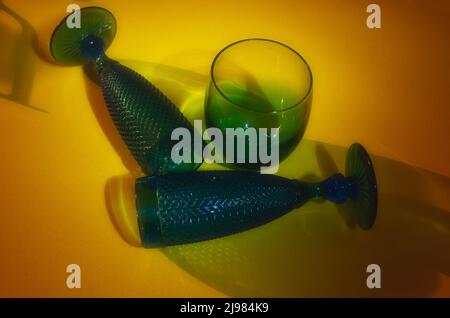 Blue glasses and green glass on yellow background Stock Photo
