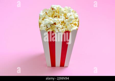 Paper striped bucket with crispy popcorn on a pink background Stock Photo