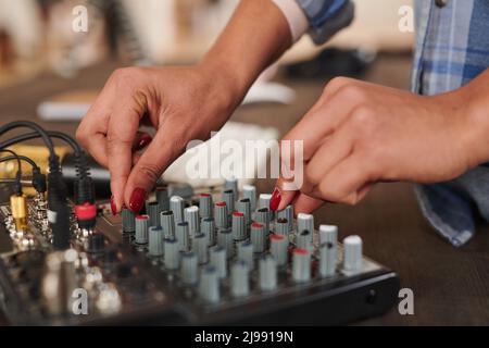 Close-up shot of unrecognizable young womans hands adjusting audio mixer setting sound in home studio Stock Photo