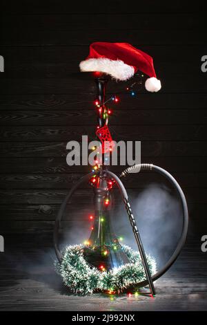 christmas hookah with glowing garland and christmas red hat on dark background Stock Photo