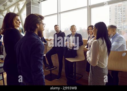 Team of happy cheerful men and women talking after business meeting in modern office Stock Photo