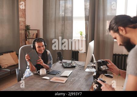 Horizontal selective focus shot of modern cameraman shooting video of young female influencer, copy space Stock Photo
