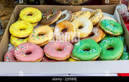 Round delicious colorful donuts in a cardboard box. Tasty round glazed cakes Stock Photo