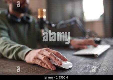 Horizontal selective focus shot of unrecognizable blogger at desk in loft room typing something on computer or playing game Stock Photo