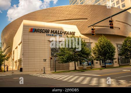 Exterior facade of unique architecture of NASCAR Hall of Fame museum in Charlotte, North Carolina with trees, signal lights, blue sky and clouds. Stock Photo