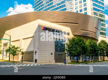 Exterior facade of unique architecture of NASCAR Hall of Fame museum in Charlotte, North Carolina with trees, signal lights, blue sky and clouds. Stock Photo