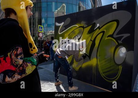 Moscow, Russia. 21st May, 2022. Artist paints graffiti on a wall during a mass bike ride in the Garden Ring in central Moscow during the spring 2022 edition of Velofest, a Moscow festival of cycling, Russia Stock Photo