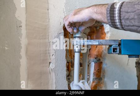 Master plumber solders the connection of plastic pipes, close up. Stock Photo