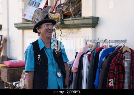 Wanganui New Zealand - April 9 2022; Man with happy smiling disposition in street outside secondhand shop  racks of clothing and other stuff on footpa Stock Photo