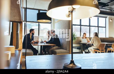 businesspeople working in a modern co-working space. Diverse business professionals having discussions while sitting in an open workspace. Entrepreneu Stock Photo