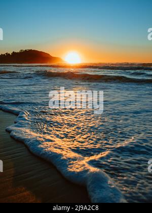 Colorful ocean beach sunrise with deep blue sky and sun rays. Stock Photo