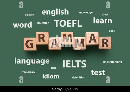 Text GRAMMAR made of wooden cubes and different words on green background. Concept of studying English Stock Photo