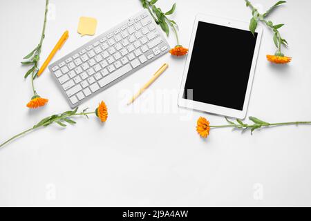 Tablet with computer keyboard, pens, sticky note and flowers on white background Stock Photo