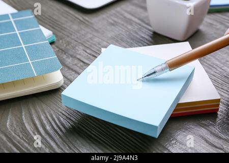 Stack of blank sticky notes and pen on grey wooden table, closeup Stock Photo