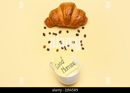 Beautiful composition with croissant, coffee beans, cup and sticky note with text GOOD MORNING on color background Stock Photo