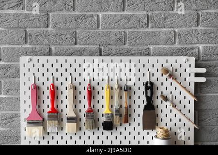 Pegboard with decorator's tools on grey brick wall, closeup Stock Photo