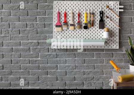 Pegboard with decorator's tools on grey brick wall Stock Photo
