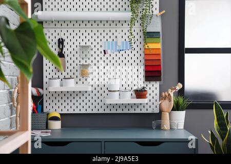 Decorator's workplace and pegboard with different tools on grey wall Stock Photo