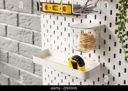 Pegboard with tools on grey brick wall, closeup Stock Photo