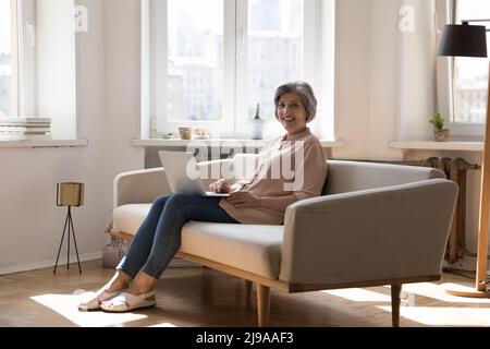 Cheerful happy mature freelancer lady using laptop Stock Photo