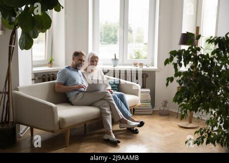 Cheerful married couple using online app on laptop computer Stock Photo