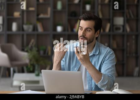 Confident male remote worker use smartphone with voice recognition app Stock Photo