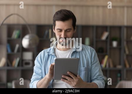 Focused casual millennial male digital tablet pc user learn online Stock Photo