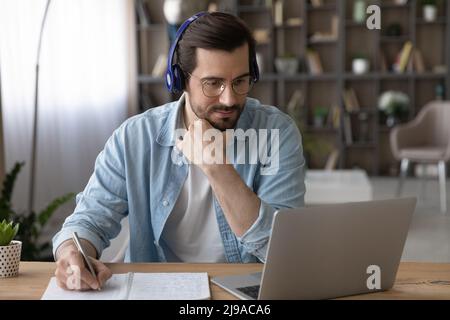 Focused male student in headphones look on pc do homework Stock Photo