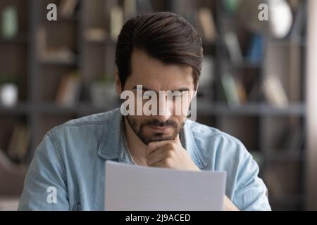 Concentrated serious male small business owner ponder on bank report Stock Photo