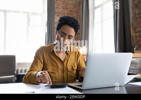 African woman sit at desk calculates bills do accountancy job Stock Photo