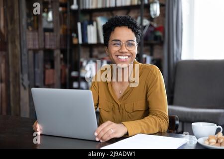 African woman distracted from working on laptop looks into distance Stock Photo
