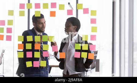 Millennial multiracial colleagues discuss creative ideas on sticky post-it notes Stock Photo