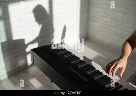 Close-up of female hands on the electric piano. Woman musician plays a keyboard instrument. Stock Photo